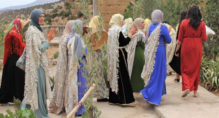 Femmes berbères en tenue traditionnelle — caftans brodés, châles à franges et bijoux en argent — lors d'une célébration dans un village des montagnes de l'Atlas marocain