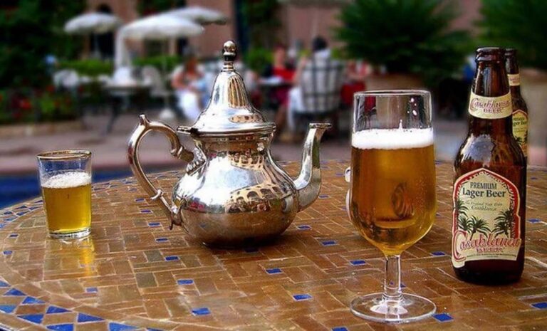 Bouteille et verre de Casablanca Beer à côté d'une théière marocaine en argent sur une table en zellige, en terrasse au Maroc