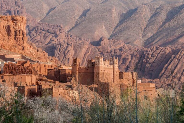 Kasbah en pisé rouge de la vallée du Dadès devant les formations rocheuses ondulées des Doigts de Singe