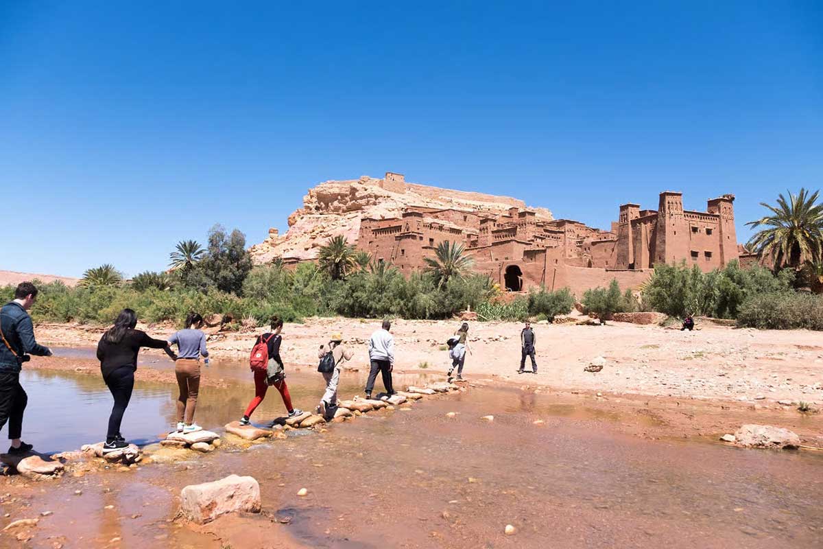 Crossing the stepping stones to Aït Ben Haddou, the fortified earthen ksar and UNESCO World Heritage Site.